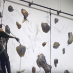woman climing wall of figures and leaving charcoal marks