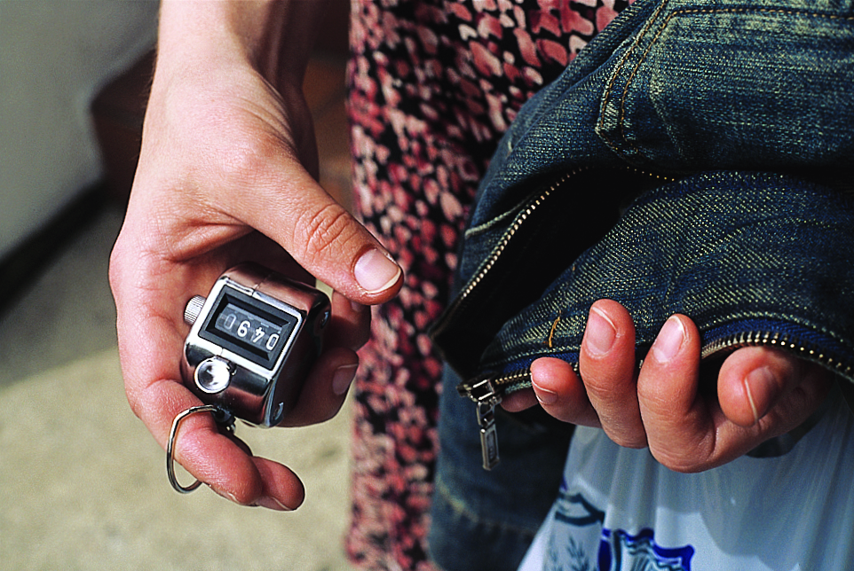 hand holding a counting device and jean jacket