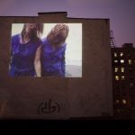 a projection of two dancers on side of a building
