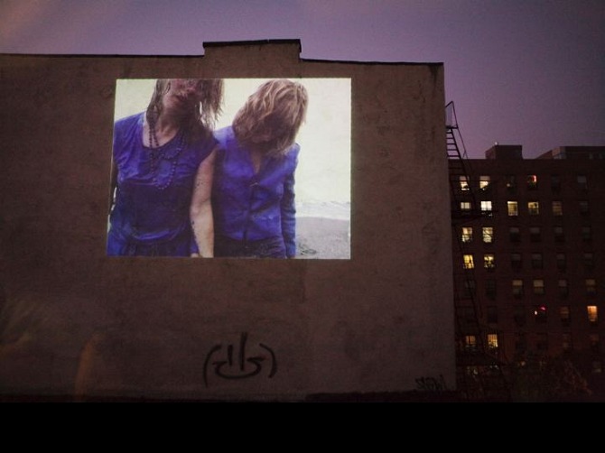 a projection of two dancers on side of a building